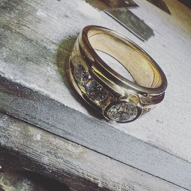 The finished ring, polished, set down on the worn wood of our bench.